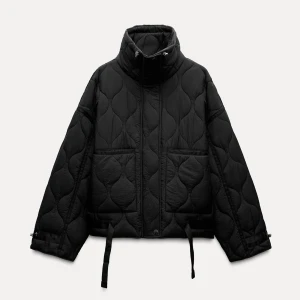 Svart quiltad pufferjacka - Säljer en snygg svart quiltad pufferjacka i mycket bra skick. Jackan har en hög krage och justerbara snören i nederkant för extra stil och värme. Perfekt för kalla höst- och vinterdagar. Den har en loose passform och långa ärmar med knäppning vid ärmsluten.