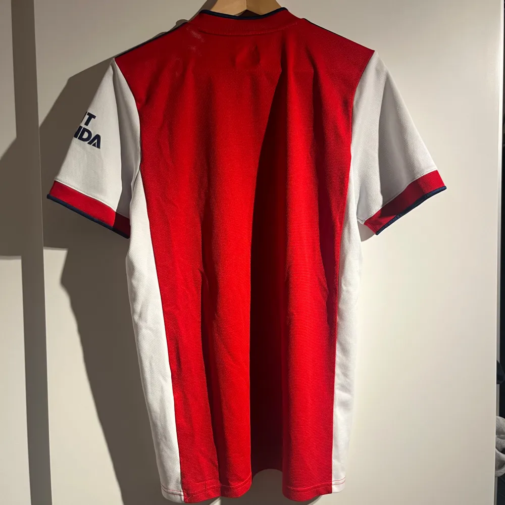 Säljer en snygg röd Arsenal fotbollströja från Adidas. Perfekt för alla Arsenal-fans! ⚽️. Sportswear.