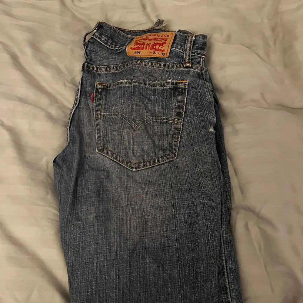 Säljer ett par klassiska Levi's 559 jeans i blå denim. De har en straight passform och är i bra skick. Perfekta för både vardag och avslappnade tillfällen. Jeansens tidlösa design gör dem till ett måste i garderoben!. Jeans & Byxor.