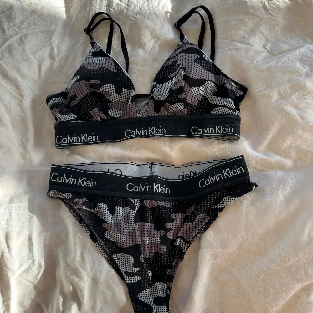 Säljer ett snyggt underklädesset från Calvin Klein i storlek S. Setet har ett coolt camouflage mönster i svart, grått och rosa. Det är gjort i mjukt material och har Calvin Klein-loggan på resåren. Perfekt för en bekväm och stilren look!. Toppar.