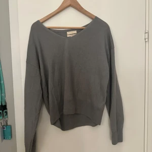 Grå kashmirtröja från H&M - Mysig grå kashmirtröja från H&M i storlek S. Perfekt för kyliga dagar med sin mjuka och lyxiga känsla. Tröjan har en v-ringad design och långa ärmar, vilket gör den både stilren och bekväm. Passar perfekt till både vardag och lite finare tillfällen.