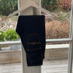 Mörkblå jeans med orange sömmar - Säljer ett par snygga mörkblå jeans från Nudie Jeans. De har coola orange sömmar och en klassisk femficksdesign. Perfekta för både vardag och fest! 🕺storlek 26/26 skick 8,5/10 ny pris 1499kr 