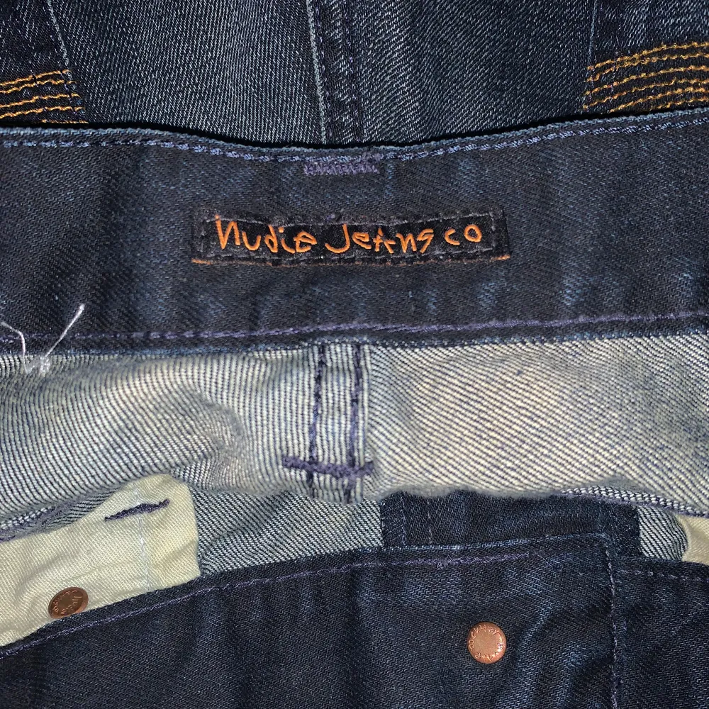 Säljer ett par snygga mörkblå jeans från Nudie Jeans. De har en klassisk femficksdesign med orange sömmar på bakfickorna. Jeansen är i nytt skick och säljs då de är för små 💗. Jeans & Byxor.