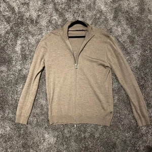 Beige merinoullskofta från Matinique - Säljer en stilren beige kofta/zip från Matinique i 100% merinoull. Den har en praktisk dragkedja framtill och är perfekt för både höst, vinter och vår. Koftan är i mycket bra skick, använd max 3 gånger. Passar lika bra till vardags som till lite finare tillfällen. Nypris på denna är 1500kr | strl L
