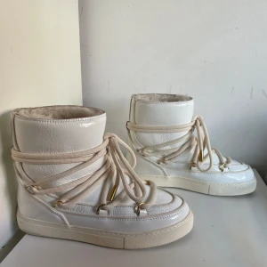 Vita boots från Inuikii - Säljer ett par snygga vita boots från Inuikii i mycket bra skick. De har en cool snörning och är perfekta för vintern. Skorna är gjorda i skinn och har en mysig insida som håller fötterna varma. Perfekta för att hålla stilen även när det är kallt ute! ❄️ använda endast en gång. 