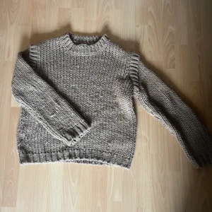 Beige stickad tröja - Mysig beige stickad tröja perfekt för kyliga dagar. Den har en klassisk design med ribbstickade muddar och en rund hals. Tröjan är i mycket bra skick och passar perfekt för både höst och vinter. Den är varm och bekväm, idealisk för att mysa i hemma eller för en promenad i parken.. Storlek L men är som S