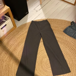 Kostymbyxor gråa randiga - Gråa kostymbyxor med vita ränder. Vida och luftiga, högmidjade. Fina.