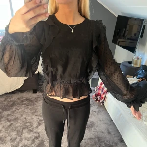 Svart blus med volanger - Säljer en superfin svart blus med volanger och prickigt mönster. 