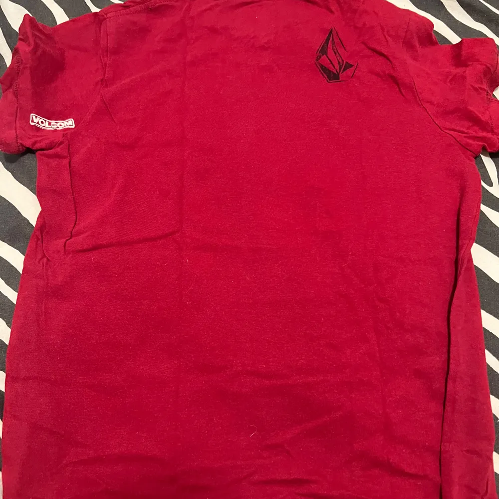 Säljer en cool röd t-shirt från Volcom i bomull. Den har ett svart tryck på framsidan och en liten logga på ärmen. Perfekt för vardagsbruk eller en avslappnad fest. Skön och stilren design!. T-paidat.