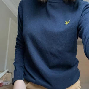 Marinblå tröja från Lyle & Scott - Säljer en marinblå tröja (kan uppfattas nästan svart i vissa ljus) från Lyle & Scott i bra skick. Den har en gul logga på bröstet och är långärmad med ribbade muddar. Notera en fläck vid höger mudd. Perfekt för höst och vinter!💙 Tviga inte vid frågor! Finns i grå och ljusare blå också på min sida. Säljer denna billigare då jag inte gillar färgen så mkt, så denna är mindre använd än de andra!