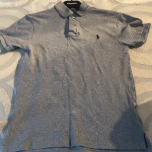 Grå polo pique - Hej där, jag säljer en jättefin polo pique i färgen grå med storlek S. Däremot har tröjan krymt och fått bröst vidden 42cm och längden 62. Detta är den perfekta tröjan till dig som bär grischiga kläder. Den är i mycket bra skick och redo för en ny ägare!