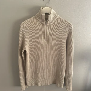 Beige tröja - Säljer en snygg beige ribbad tröja från Jack & Jones. Den har en dragkedja vid halsen och är perfekt för kyliga dagar. Tröjan är i mycket bra skick och passar både till vardags och lite finare tillfällen. Perfekt för höst och vinter! Nypris 599! Mitt pris 149, i väldigt bra skick.