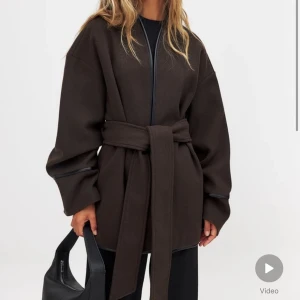 Brun kappa med bälte - Snygg brun kappa med bälte. Perfekt för höst och vår. Den har långa ärmar och en stilren design utan mönster. Passar både till vardags och festliga tillfällen. Nyköpt med prislappen kvar då jag har en likande. Storlek 34 men passar allt från 32-38. Nypris 1099, sälker för 800!
