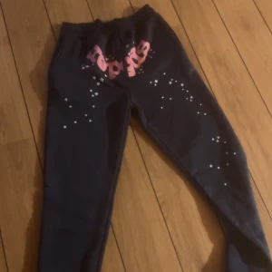 Svarta mjukisbyxor med stjärnor - Säljer ett par svarta mjukisbyxor med coola stjärnor och textdetaljer i rosa. Perfekta för en avslappnad dag hemma eller en snabb tur till affären. Byxorna har en bekväm passform och snörning i midjan för extra komfort. Passar perfekt till höst- och vintermys!