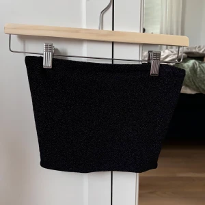 Svart glittrig tubtopp  - Snygg svart glittrig tubtopp från Gina Tricot i storlek S. Perfekt för festliga tillfällen med sin glittriga yta. Glittret fäller inte. Använd en gång så toppen är i mycket bra skick och har en tight passform som sitter bekvämt. Översidan har silikonband för att sitta bra (bild 4) och är perfekt till en stilren look🥰
