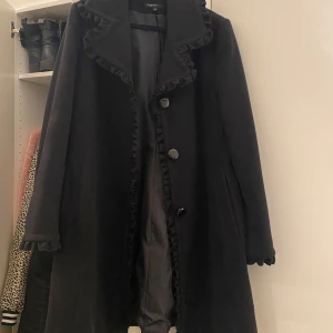 Kappa - En mkt fin kappa med volanger. Det finns ett hål i ena fickan, vilket är lätt att laga.