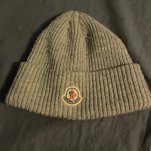 Grå mössa från Moncler -  Moncler mössa, den e använd men inga skador elle hål i den😀