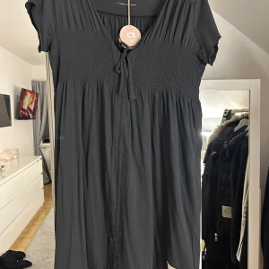 Svart klänning från Odd Molly - Snygg svart klänning från Odd Molly med korta ärmar och knytning framtill. Perfekt för en avslappnad stil med en touch av elegans.