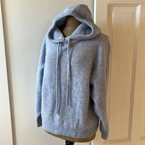 Ljusblå stickad hoodie - Mysig ljusblå stickad hoodie med luva och dragsko. Perfekt för kyliga dagar med sin avslappnade passform och långa ärmar. En stilren och bekväm tröja för alla tillfällen.