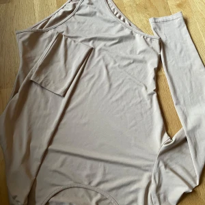 Beige långärmad topp - Snygg beige långärmad topp med en stilren design. Perfekt för en avslappnad look. Tillverkad i ett mjukt och bekvämt material.