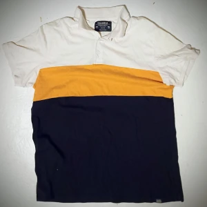 Randig pikétröja från Pull & Bear - Säljer en snygg pikétröja från Pull & Bear i tre färger: vit, gul och svart. Tröjan har korta ärmar och en klassisk krage med knappar. Perfekt för en avslappnad stil.