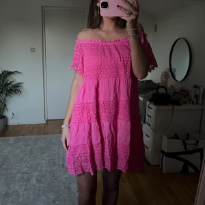Rosa offshoulder klänning - Charmig rosa offshoulder klänning med volangdetaljer. Perfekt för sommarens varma dagar.