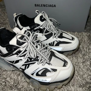 Balenciaga sneakers  - Snygga Balenciaga sneakers i svart och vit med snörning. Skorna har en modern design med tydliga Balenciaga-loggor och en robust sula. Perfekta för en trendig look.