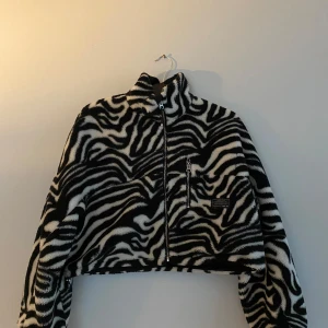 Zebramönstrad croppad jacka från Bershka - Säljer min zebramönstrade croppad jacka från Bershka. Jackan har en dragkedja framtill och en hög krage.