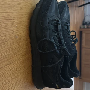 Svarta sneakers från Reebok - Säljer ett par svarta Reebok sneakers i slitstarkt material med snörning. Skorna har en diskret design med Reebok-logga och är tillverkade med Cordura för extra hållbarhet. Perfekta för vardagsbruk. Använda ett få tal gånger säljs pågrund av att dom är för små