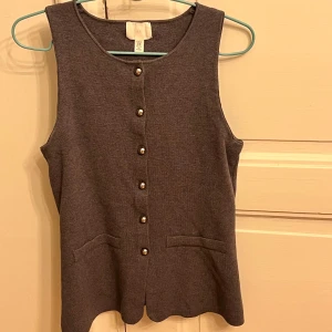Grå väst från H&M - Snygg grå väst från H&M med knappar framtill. Perfekt för lager-på-lager-stil och passar till många olika outfits. Enkel och stilren design.