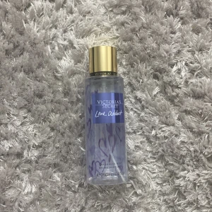 Victoria's Secret Love Addict Fragrance Mist - En doftspray från Victoria's Secret med namnet Love Addict. Flaskan är lila med ett guldlock och rymmer 250 ml. Perfekt för den som älskar en fräsch och blommig doft.