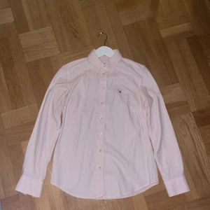 Rosa randig skjorta från GANT - Säljer en stilren rosa och vit randig skjorta från GANT. Skjortan har långa ärmar och knappar framtill. Den är sparsamt använd. 