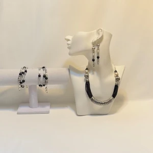 Smyckeset med halsband, armband och örhängen - Elegant smyckeset med ett halsband, armband och örhängen i silver och svart. Halsbandet har en unik design med svarta pärlor och silverdetaljer. Armbanden matchar med liknande pärlor och örhängena kompletterar setet med stilrena hängen. Ett par örhängen och ett par armband plus en halsband handgjorda mycket mycket fint nytt oanvänd 