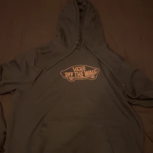 Mörk grön hoodie från Vans - Säljer en mörk grön hoodie från Vans med det klassiska 'Off the Wall' trycket på bröstet. Tröjan har en justerbar huva och en stor ficka framtill. Nästan aldrig använd. Nypris 540