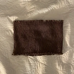 Brun tubtopp från SOC - Säljer en brun tubtopp från SOC i en smockad design. Toppen är elastisk och sitter tight, perfekt för sommarens varma dagar. Den är ärmlös och har en croppad längd som passar bra till höga jeans eller kjolar. Aldrig använt toppen💕