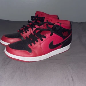 Nike Air Jordans i rött och svart - Snygga Nike Air Jordans i en klassisk röd och svart färgkombination. Skorna har en hög modell med snörning och den ikoniska Nike-loggan på sidan. Perfekta för dig som vill ha en stilren och sportig look.