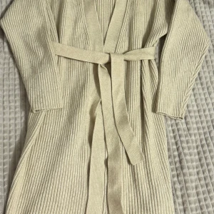 Beige ribbad kofta med bälte - Säljer en stilren beige ribbad kofta med bälte i midjan. Perfekt för kyliga dagar och ger en avslappnad men elegant look. Långärmad design som passar bra till både jeans och klänning. Om ni vill se den på, skriv gärna!