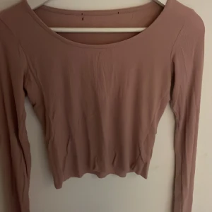 Rosa ribbad långärmad topp - Säljer en rosa ribbad långärmad topp med rund halsringning. Toppen är croppad och har en tight passform.