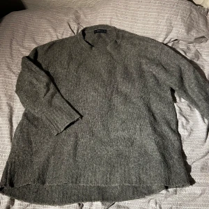 Grå stickad tröja från Zara - Mysig grå stickad tröja från Zara med en avslappnad passform. Lite oversize. Perfekt för kyliga dagar med sin mjuka och bekväma design. Tröjan har långa ärmar och en enkel stil som passar till det mesta.