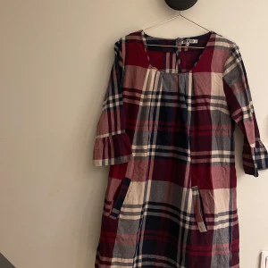 Quicksilver Klänning  - Måttligt använd. Storlek L. Mjuk, med fickor och lite öppet vid ryggen. Vinröd, blå och ljus beige.