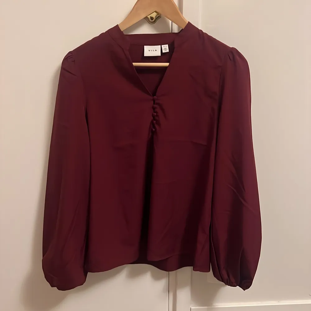 Söt blus med mininal, diskret puffärm. 5 knappar framtill som går att knäppa upp. Resår i armarna nedtill. Oanvänd. . Puserot.