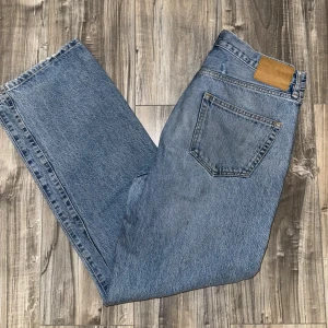 Blå jeans från 157 - Säljer ett par klassiska blå jeans från 157. De har en straight passform och är tillverkade i denim. Perfekta för en avslappnad stil. jeansen använda, men väljer att sälja dem eftersom att det inte längre passar mig som de gjorde innan. Jeansen har en  defekt så man kan se på första bilden vid midjan ungefär. är 185 och jeansen börjar bli för små och därför väljer jag att sälja dem