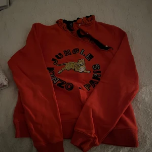 Orange hoodie från Kenzo x H&M - Galet snygg tröja från kenzo, knappt använd så skicket är som ny!! Xs men passar perfekt för mig som valigtvis har s-m!! Säljer då den tyvärr bara ligger i garderoben och behöver en ny ägare:)