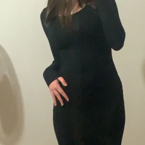 Svart långklänning - Elegant svart långklänning med långärmad design. Klänningen har en tight passform som framhäver figuren och är perfekt för en stilren look.