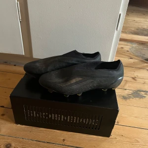 Svarta fotbollsskor - Snygga svarta fotbollsskor med en strömlinjeformad design. Skorna har en diskret mönstring och är perfekta för snabba rörelser på planen. De är tillverkade i syntetmaterial för hållbarhet och lätthet.