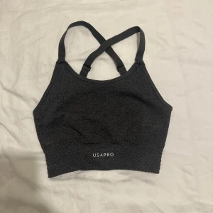 Mörkgrå sporttopp från USA Pro - Snygg mörkgrå sporttopp från USA Pro med korsade axelband. Perfekt för träning med sin bekväma passform och stilrena design.