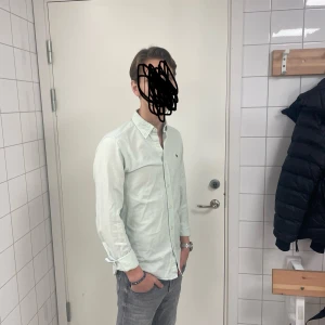 Morris skjorta - Säljer en stilren ljusgrön skjorta från Morris med en liten broderad detalj på bröstet. Skjortan har långa ärmar och knappar framtill. Perfekt för en snygg och avslappnad look.