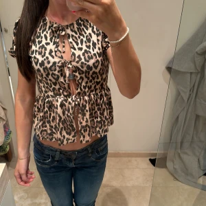 Leopardmönstrad blus med knytning - Trendig leopardmönstrad blus med korta ärmar och knytningar. Blus från Gina tricot som inte finns längre. Väldigt bra skick bara använd 1-3 gånger. Storleken är 146/152 men passar mig som är S