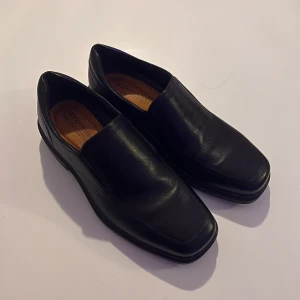 ECCO HELSINKI Loafers - Snygga och stilrena svarta loafers från Ecco i skinn. Perfekta för en elegant look med bekväm passform och robust sula. Enkla att ta på och av, vilket gör dem praktiska för dagligt bruk.