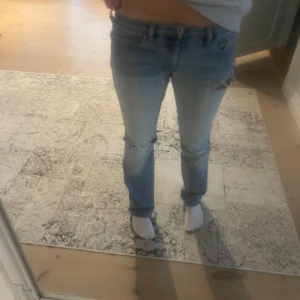 Blå jeans med slitningar - Säljer ett par blå jeans från disel med slitningar på knäna. De har en klassisk femficksdesign och är lågmidjade. Perfekta för en avslappnad stil. Midjemåttet: 37 cm och innerbenslängden: 80cm